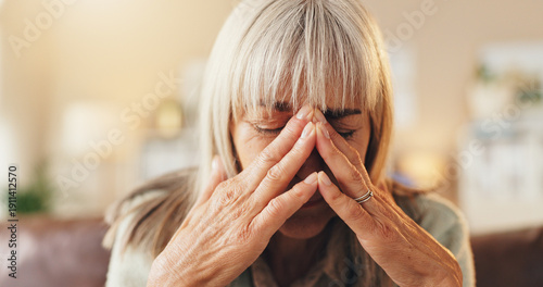 Photos Anxiety, headache or psychology with senior woman on sofa in living room of home for mental health