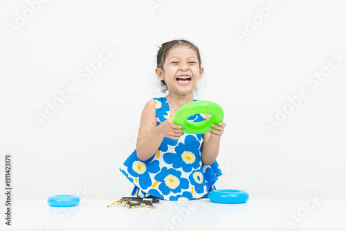 Cute Asian girl playing with toys and laughing happily on white background.