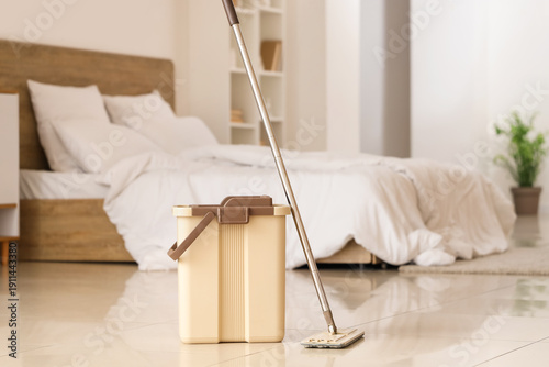 Mop with bucket on tile floor in bedroom
