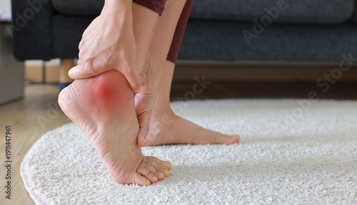 Canvas Print Woman standing and massaging her painful heel with red highlight