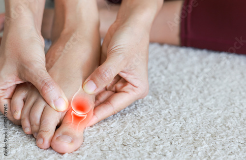 Fotografi Close up of woman massaging painful big toe with anatomical joint illustration and red highlight