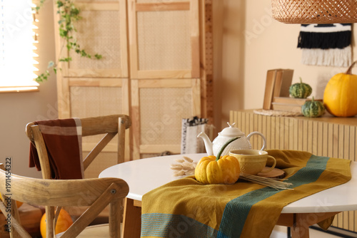 Konstfotografi Pumpkin, teapot and cup on table in interior of dining room, closeup