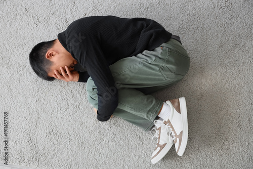 Sad young Asian man lying o...