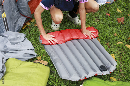 Quadro su tela Focused person on grass preparing camping gear for an outdoor adventure, careful