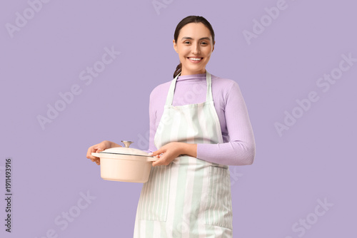 Young woman in apron holdin...