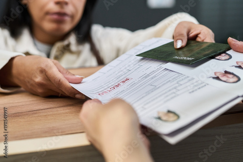 Cuadro en lienzo Woman handing over rejected visa application form and passport to another across