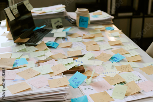 Canvastavla Office desk covered with scattered sticky notes and paperwork, closed laptop and