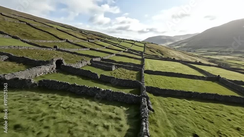 A landscape featuring terraced fields enclosed by stone walls, on a green hillside