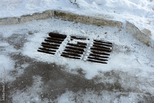 Frozen water drainage grate on a snowy road