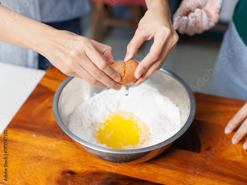 Closeup hand of woman cracking egg over mixing stainless bowl prep different fresh ingredients pour flour measuring process making homemade dessert bread pastry recipe baking cooking in bakery kitchen