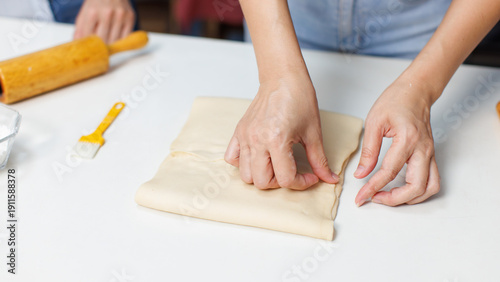 Closeup hand of woman bakers preparing knead dough with butter on white table counter process making pastry pie workflow ingredients flour homemade sweet dessert bread baking cooking in bakery kitchen