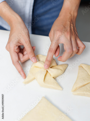 Closeup hand of woman bakers chef shaping folding puff pastry dough pie on white table process making workflow ingredients flour delicious homemade sweet dessert bread baking cooking in bakery kitchen