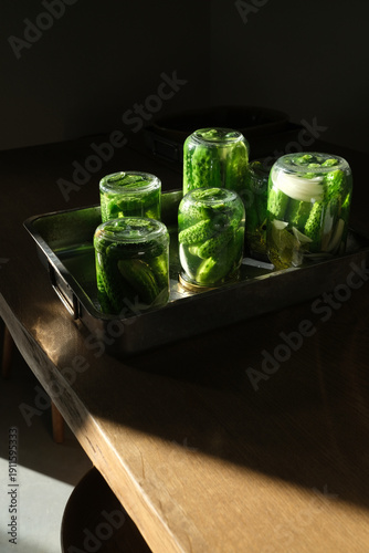 Upside down glass jars with fermenting cucumbers in natural light