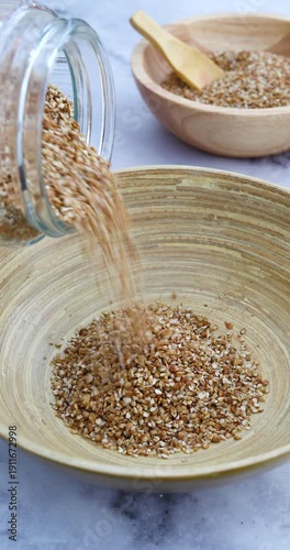 Pouring broken buckwheat groats into a deep bowl