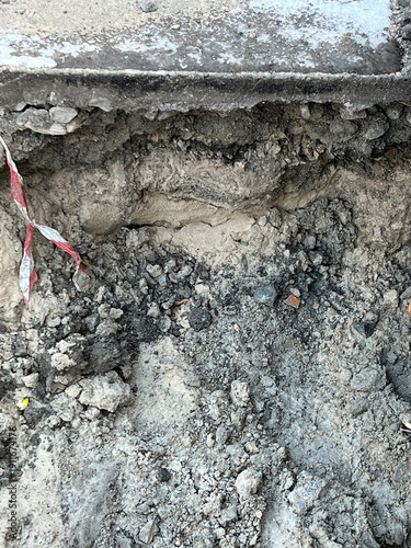 Damaged sidewalk or road edge showing layered soil and broken asphalt Kyiv
