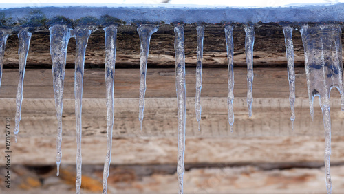 Принти на полотні Large icicles hang from the roof, shine in the sun, water drips from them