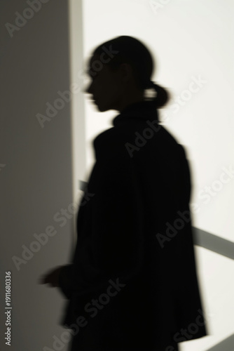 Wallpaper Mural A minimalist fashion photograph capturing a female model in silhouette with her face turned away and partially obscured by darkness. The composition uses intentional blur and cropped Torontodigital.ca