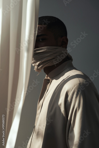 Wallpaper Mural A refined portrait photography setup showing a male model in modest attire with his face intentionally covered by fabric and partially hidden in shadow. Cropped composition focuses Torontodigital.ca