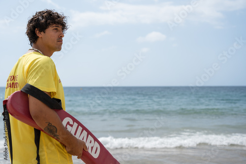 Foto Lifeguard watching over swimmers holding rescue buoy on beach