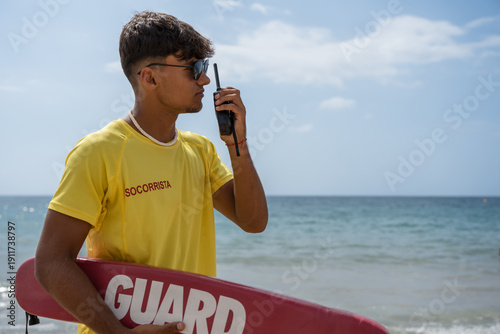 Cuadro en lienzo Lifeguard using walkie-talkie on the beach during summertime