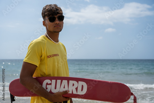 Cuadro en lienzo Lifeguard standing on the beach holding rescue buoy