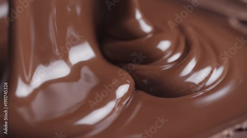 Rich delicious melted dark chocolate pouring creating glossy sweet dessert swirls close up