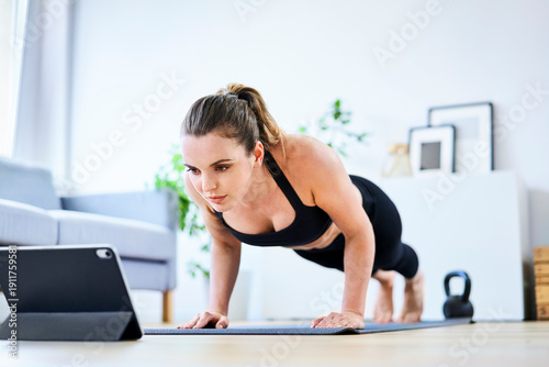 Woman learning exercise on internet through tablet PC at home