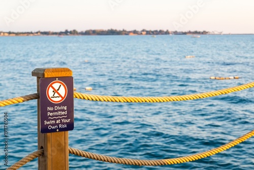 No diving sign by ocean waterfront