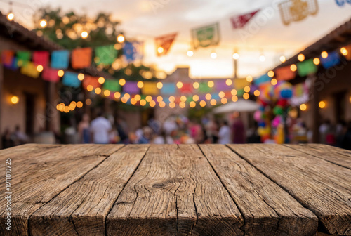 Empty rustic wooden table top with blurred background of colorful Mexican fiesta party decoration and lights for Cinco de Mayo celebration mock up or restaurant menu display