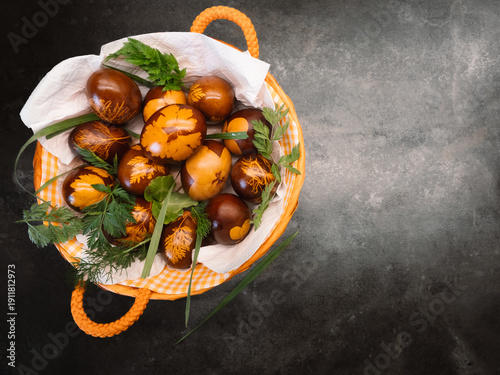 Photos Rustic basket with naturally dyed Easter eggs and green leaves