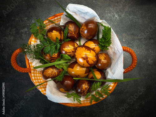 Photos Rustic basket with naturally dyed Easter eggs and green leaves