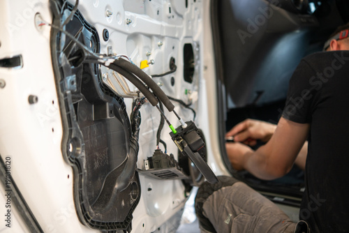 Technician repairing car door wiring inside auto body shop