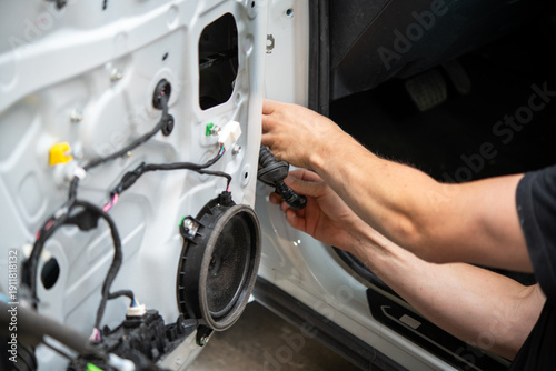 Technician repairing car door wiring inside vehicle body shop
