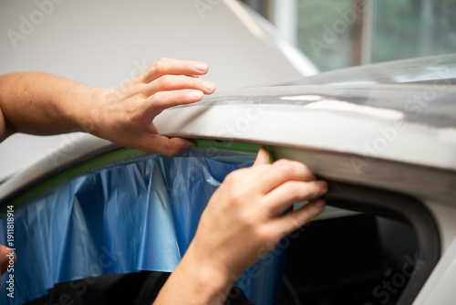 Fotografi Closeup of hands masking car window in auto body shop