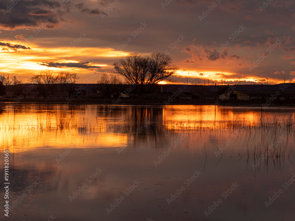 Obraz premium Sunset over the pool in Loreto, Huesca with golden reflections and colorful sky. Ideal image for tourism, summer and relaxation concepts in Spain.