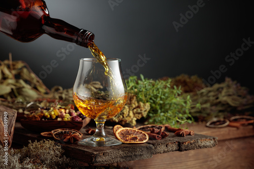 Herbal bitter liqueur is poured from a vintage bottle into a glass.