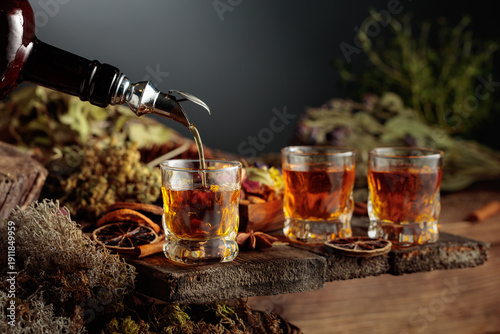 Foto Herbal bitter liqueur is poured from a vintage bottle into a glass