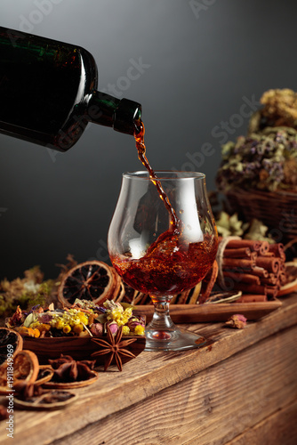 Photos Herbal balm or tincture is poured from a vintage bottle into a glass