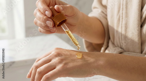 A woman applies natural face serum from a dropper onto her hand, showcasing a healthy skincare routine in soft natural light.