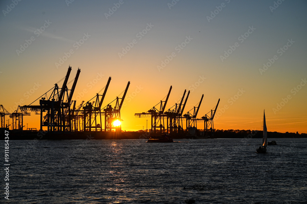 Obraz premium Port of Hamburg, Germany. Silhouettes of cranes in the port at sunset. Industry and transport. Port of Hamburg.