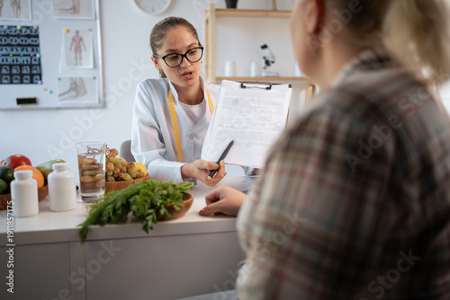 Female nutritionist explaining personalized meal plan to overweight patient during healthcare consultation. dietitian showing nutrition plan