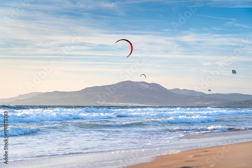 Kitesurfers at sunset in Tarifa with the mountains in background off the coast Spain, surfing spot in Europe, Andalusia.