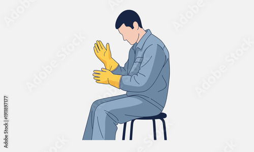 A worker in a grey uniform sitting and carefully pulling on a pair of bright yellow protective safety gloves.