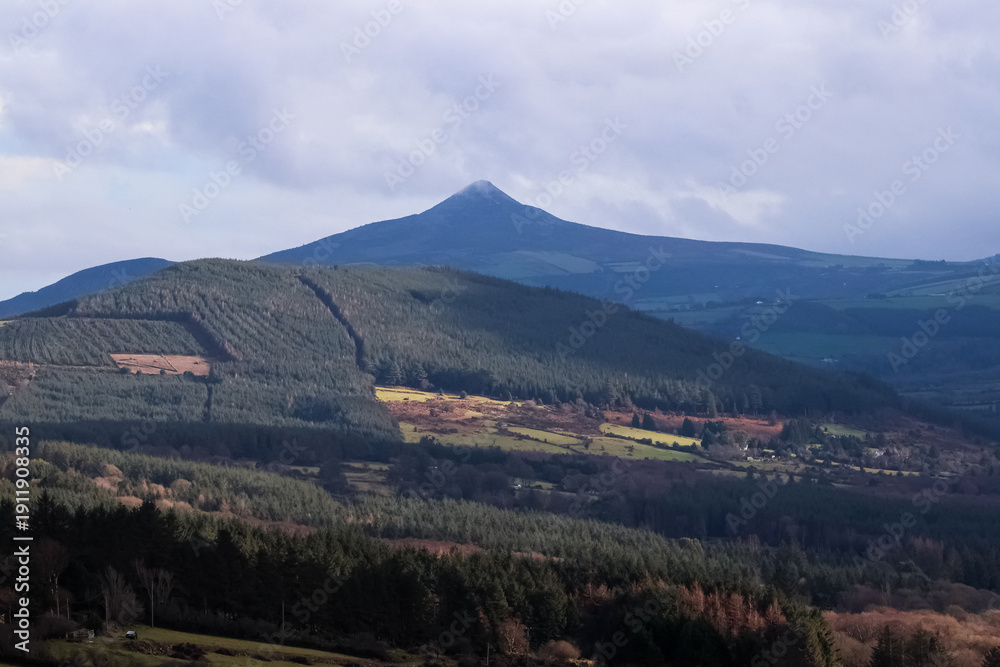 Obraz premium Vibrant rainbow over the Wicklow Mountains in Ireland against a dark, moody sky. Dramatic highland landscape during stormy weather.