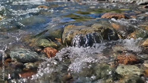 A close-up view of a small waterfall cascading over smooth, colorful rocks.