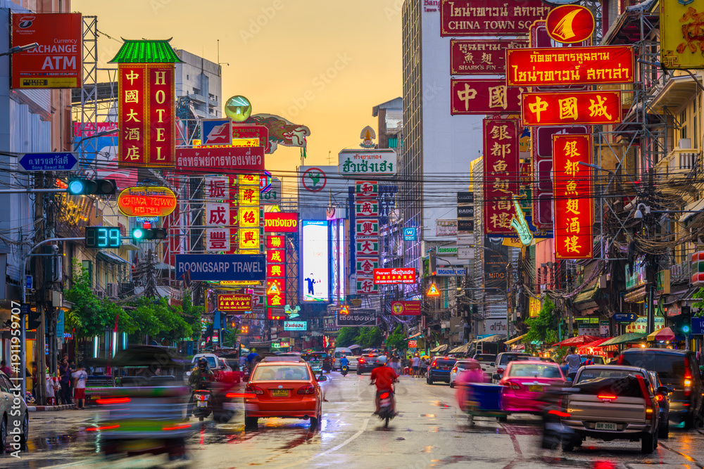 Naklejka premium BANGKOK, THAILAND - SEPTEMBER 27, 2015: Traffic on Yaowarat Road passes below lit signs in the Chinatown district at dusk. 