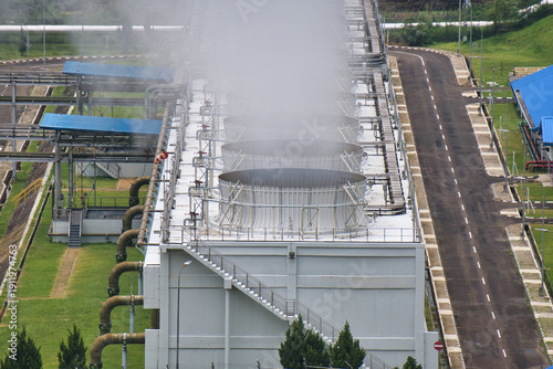 Obraz na plátně Aerial view of a geothermal power plant with cooling towers emitting steam, surrounded by green landscape and industrial infrastructure