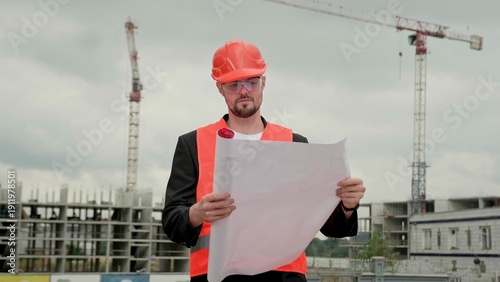 Supervisor with big plan working at construction site