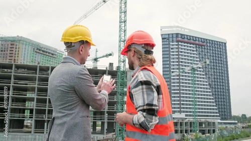 Photos General contractor and subcontractor using smartphone during site inspection
