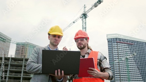 Photos General contractor and subcontractor using laptop during site inspection